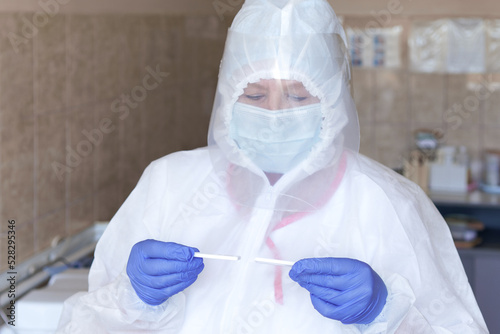 Woman scientist wearing protective costume  screen  gloves working in laboratory making a covid test. Female researcher doing investigations using special equipment with test tubes  glass and solution