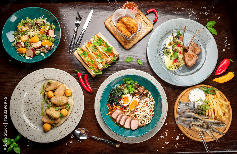Different colorful meals on dark wooden table in the restaurant. Different colorful meals on dark wooden table in the restaurant.