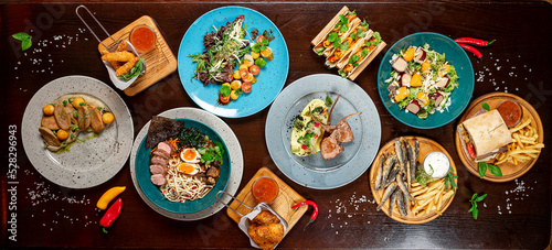 Εκτύπωση καμβά Different colorful meals on dark wooden table in the restaurant.