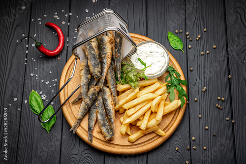 Small fried fish and french fries at an seaside restaurant. Fried anchovies