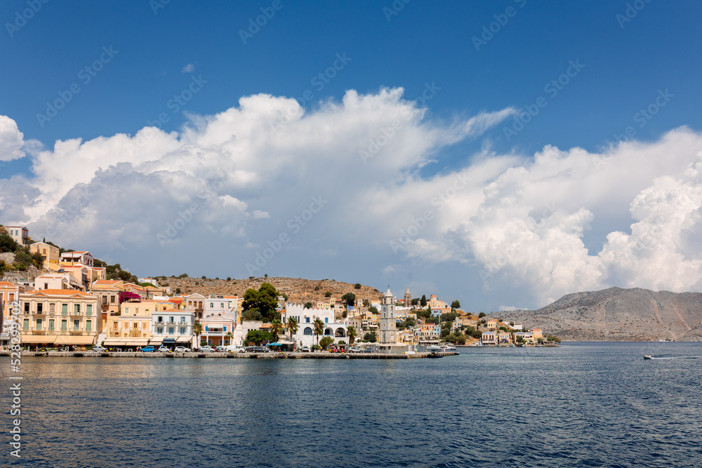 Panoramic view, aerial skyline of small haven of Symi island. Village with tiny beach and colorful houses located on rock. Tops of mountains on Rhodes coast, Dodecanese, Greece . High quality photo