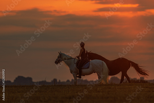 silhouette of a young woman riding a horse