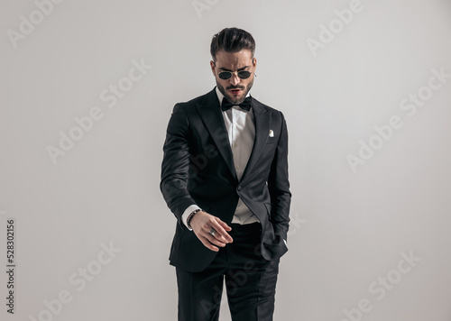 sexy young groom with glasses looking down and holding hand in pocket