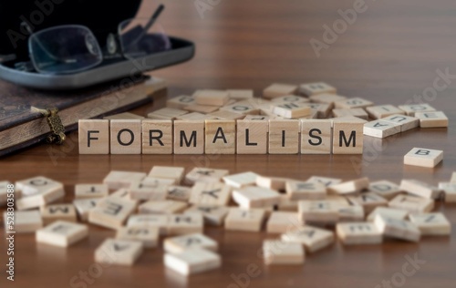 formalism word or concept represented by wooden letter tiles on a wooden table with glasses and a book photo