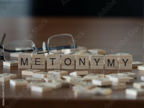 metonymy word or concept represented by wooden letter tiles on a wooden table with glasses and a book photo