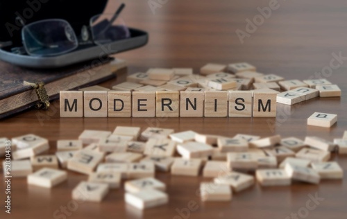 modernism word or concept represented by wooden letter tiles on a wooden table with glasses and a book