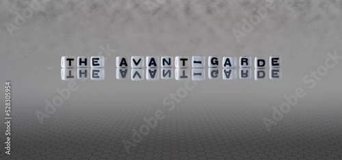 the avant garde word or concept represented by black and white letter cubes on a grey horizon background stretching to infinity
