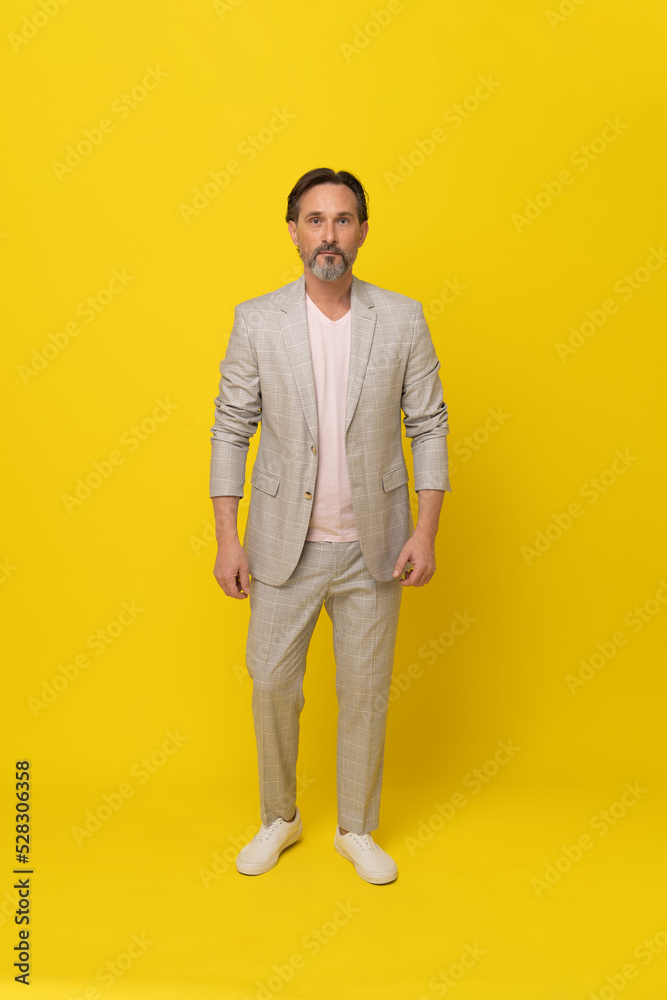 Handsome businessman in white suit. Middle aged business man in white, grey casual suit folded arms smiling looking at camera isolated on yellow background. Business concept. 