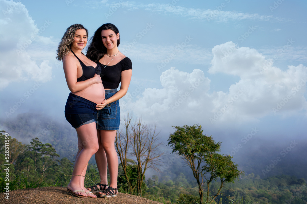 pregnant lesbian couple showing belly outdoors. pregnant lesbian couple showing belly outdoors.