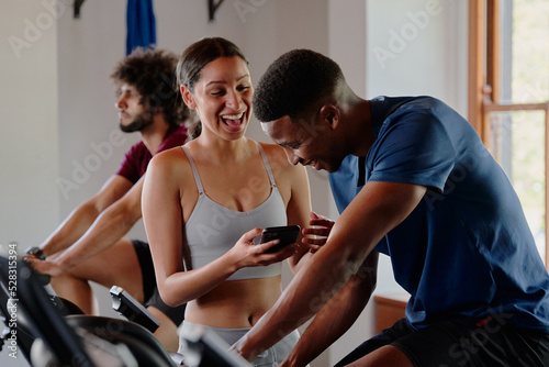Group of young multiracial friends laughing while using mobile phone at the gym