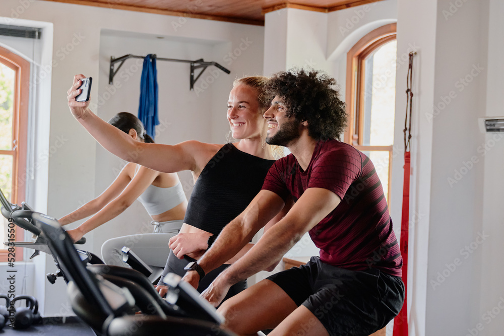Obraz premium Group of young multiracial friends taking selfie with mobile phone at the gym