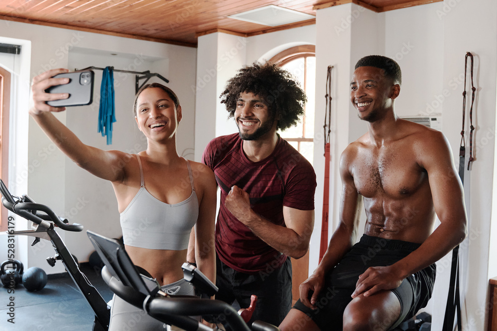 Group of young multiethnic friends taking selfie with mobile phone at the gym Group of young multiethnic friends taking selfie with mobile phone at the gym