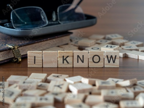 i know word or concept represented by wooden letter tiles on a wooden table with glasses and a book