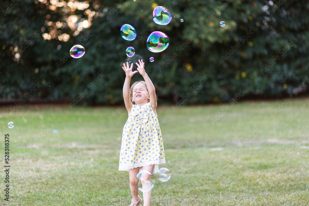 Little girl catching bubbles in the park