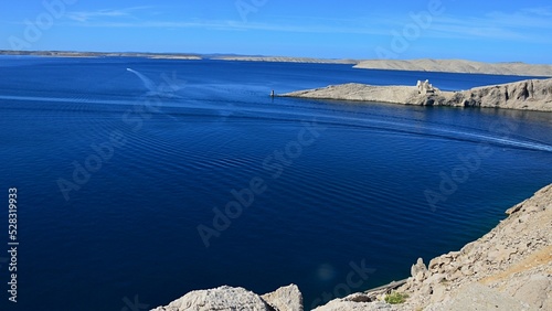 Northwestern view from Pag island bridge, northern Dalmatia, Croatia, Adriatic,  on deep blue waters and foreland cape and ruins of Fortica medieval fort, summer sunny day of august 2022.