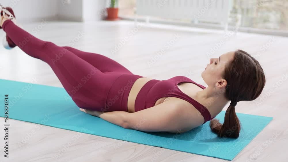 a beautiful and athletic girl in a burgundy tracksuit does exercises for stretching muscles a beautiful and athletic girl in a burgundy tracksuit does exercises for stretching muscles