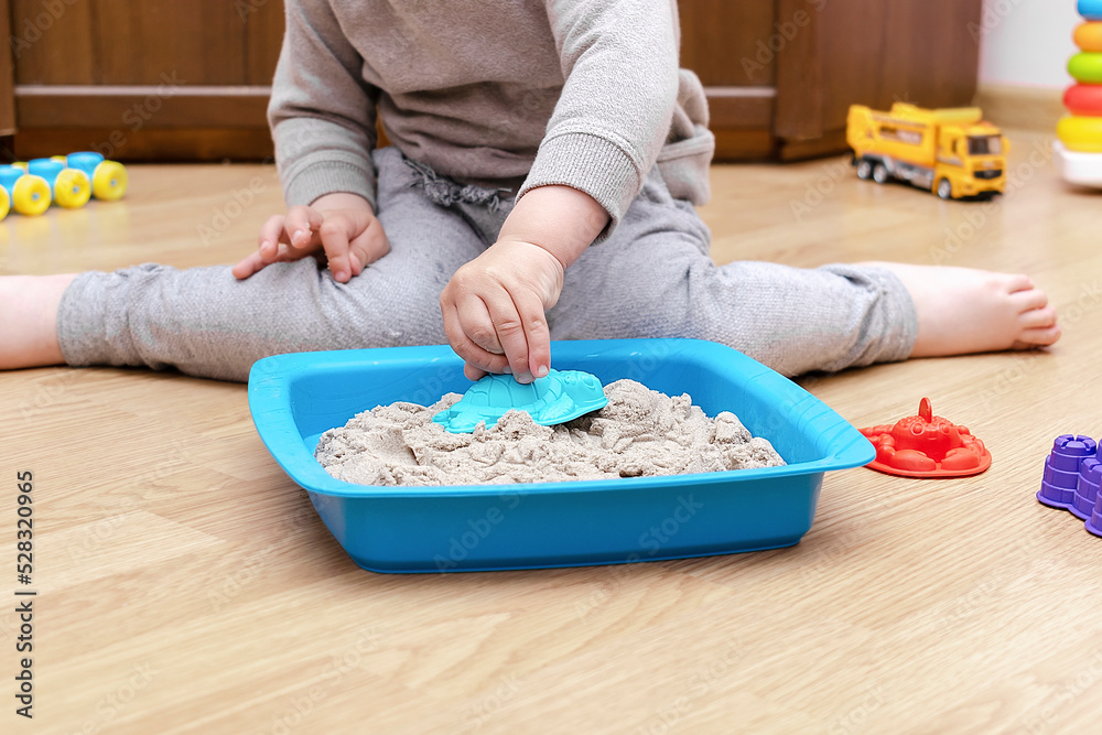 little child boy playing at home in sensory box with kinetic sand.Development of fine motor skills. Early sensory education. Activities Montessori.art creativity, craft at daycare,kindergarten little child boy playing at home in sensory box with kinetic sand.Development of fine motor skills. Early sensory education. Activities Montessori.art creativity, craft at daycare,kindergarten