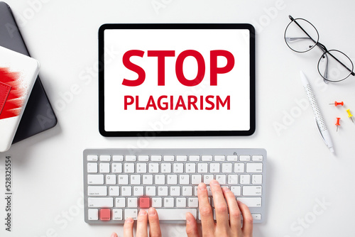 Stop plagiarism concept. Female hands on keyboard with lighted keys control c, digital tablet with sign STOP PLAGIARISM on screen.