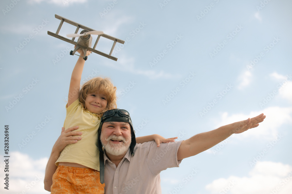 Grandfather and grandson having fun with plane outdoor on sky background with copy space. Child dreams of flying, happy childhood with granddad. Grandfather and grandson having fun with plane outdoor on sky background with copy space. Child dreams of flying, happy childhood with granddad.
