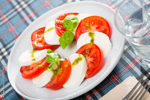 .Light salad with young cheese and tomatoes with pesto sauce