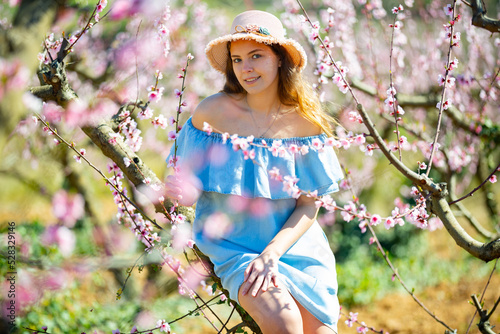 Girl in the spring garden peach in a blue dress and hat
