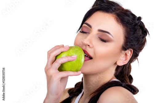 Beautiful young brunette girl eating a green fresh apple isolated on white background