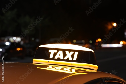 Taxi car with yellow sign outdoors at night