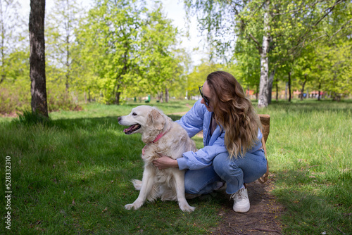 Young beautiful woman and her golden retriever dog having fun in spring