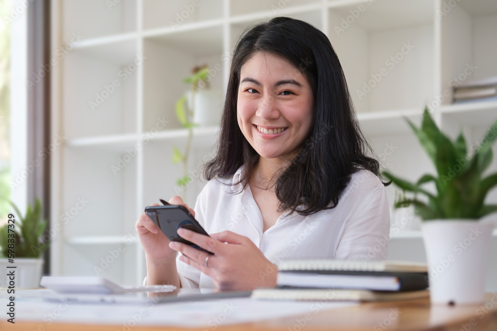 Asian female employees checking social media, reading online news on her smart phone.. Asian female employees checking social media, reading online news on her smart phone..