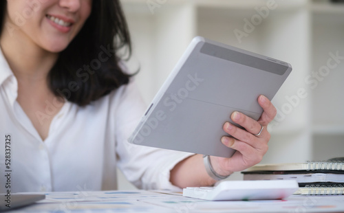 Cropped shot businesswoman sitting in modern office and using digital tablet..