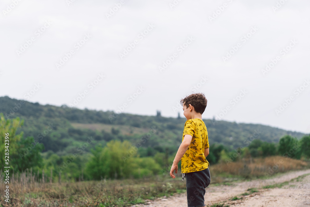A six-year-old boy runs in the countryside. Happy child boy laughing and playing in the summer day.