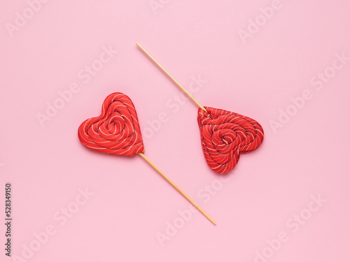 Two red heart-shaped candies on a pink background. Minimal concept of sweet life and love.