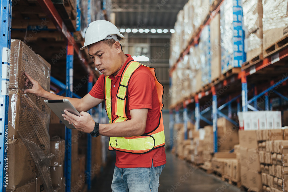 Warehouse workers checking stock with digital Tablet in Logistic center. Asian male manager wearing safety vests to working about shipment in storehouse, Working in Storage Distribution Center.