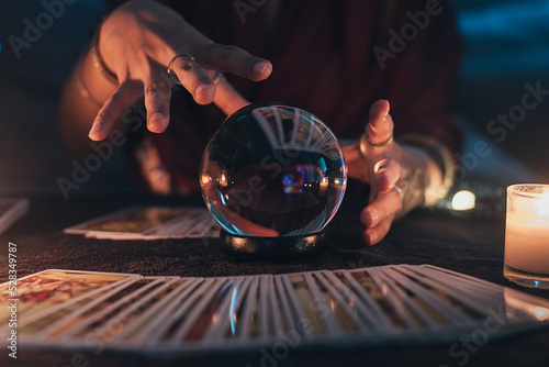 Fortune teller with illuminated crystal ball and tarot cards to prediction future. Hands of astrologists reading future and destiny. Horoscope and forecasting concept. photo