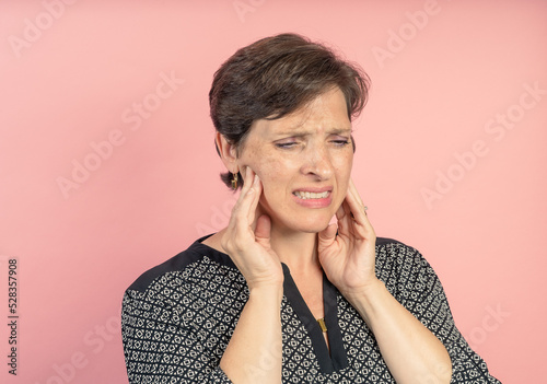 Brunette woman in her 50s in the studio with a pink background with TMJ issues