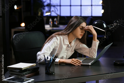 Bild auf Leinwand Tired businesswoman working with laptop in office at night