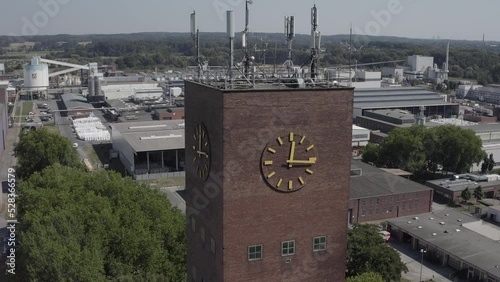 Rückwärstflug  weg von einem Uhrenturm hinter dem sich eine große Industrieanlage öffnet
  photo