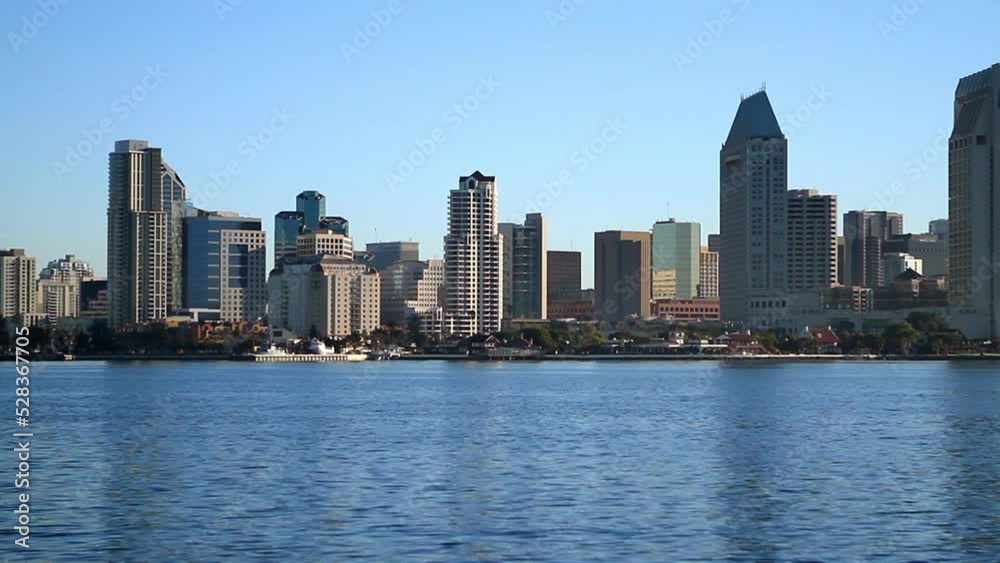 Aerial: Panning Shot Of High-Rise Condo Buildings Against Clear Sky, Drone Flying Over Rippled Water - San Diego, California Aerial: Panning Shot Of High-Rise Condo Buildings Against Clear Sky, Drone Flying Over Rippled Water - San Diego, California