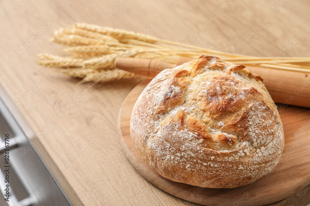 Naklejka premium Cutting board with fresh bread on table in kitchen, closeup