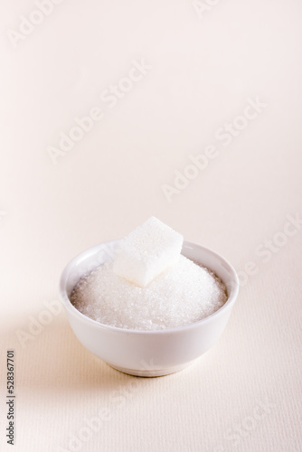 Bowl with granulated sugar and a cube. Choosing between types of sugar. Vertical view