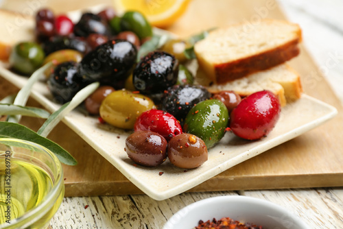 Plate of delicious olives on table, closeup