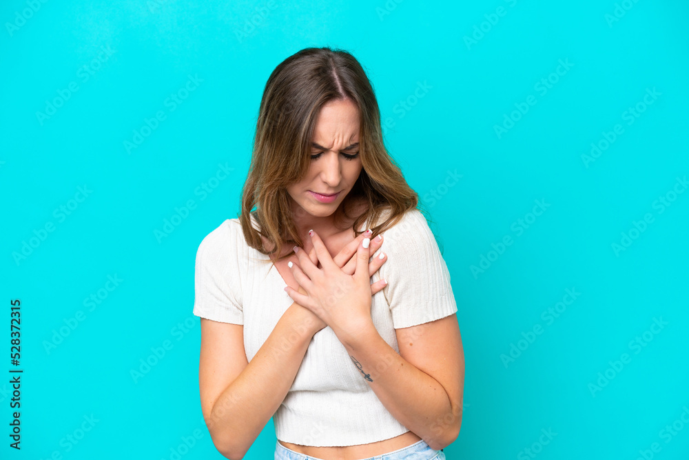 Young caucasian woman isolated on blue background having a pain in the heart