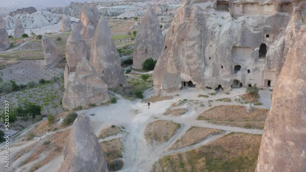 Man flying through fairy chimneys towards traditional rock church in Cappadocia Turkey Man flying through fairy chimneys towards traditional rock church in Cappadocia Turkey