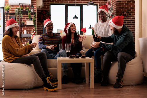 Multiethnic group of people drinking glasses of wine to celebrate winter holiday at christmas party festivity. Colleagues with alcoholic beverage having fun at xmas event in festive office.