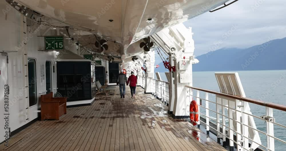 Life boat deck Promenade cruise ship couple Alaska. Luxury beautiful cruise ship vacation in Alaska inside passage. High priced all inclusive travel. International travel.
