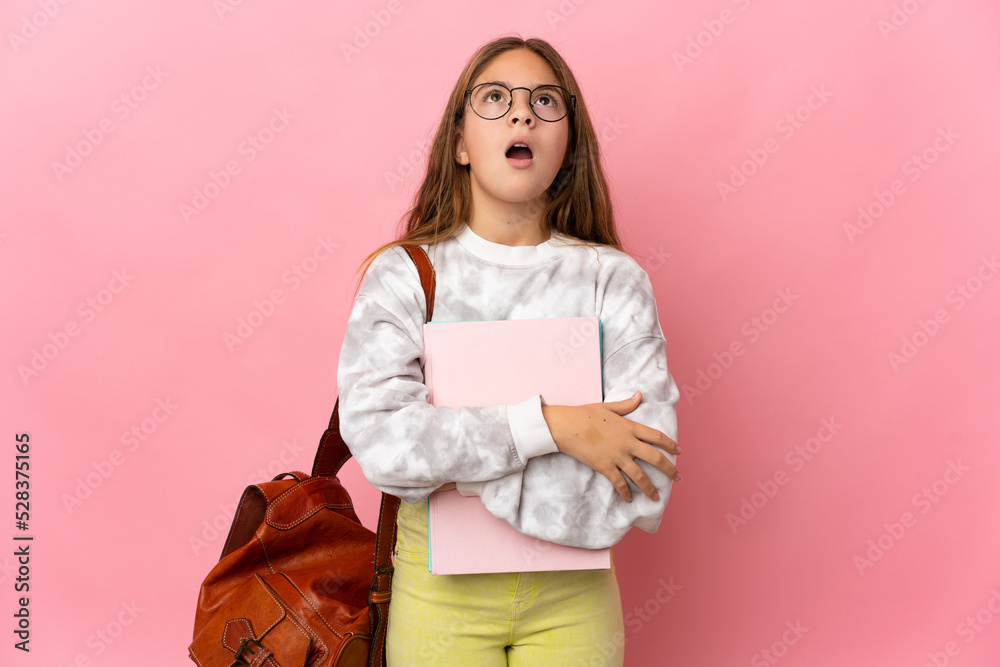 Student little girl over isolated pink background looking up and with surprised expression Student little girl over isolated pink background looking up and with surprised expression