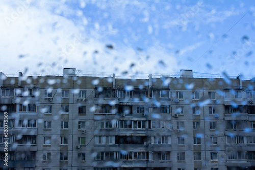 Multi-storey building viewed through a wet window with drops  rain in the city