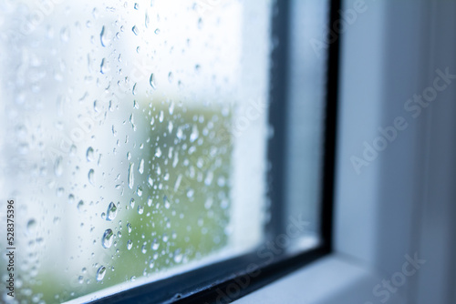 Drops on the glass close-up, rain outside the window, wet double-glazed window, selective focus