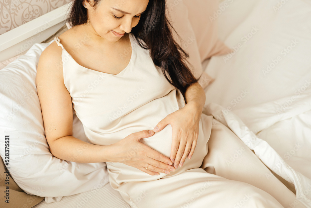 A beautiful pregnant girl strokes her stomach in a home interior. A beautiful pregnant girl strokes her stomach in a home interior.