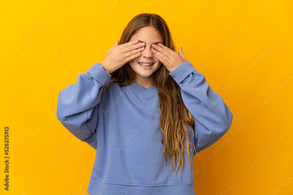 Child over isolated yellow background covering eyes by hands and smiling Child over isolated yellow background covering eyes by hands and smiling